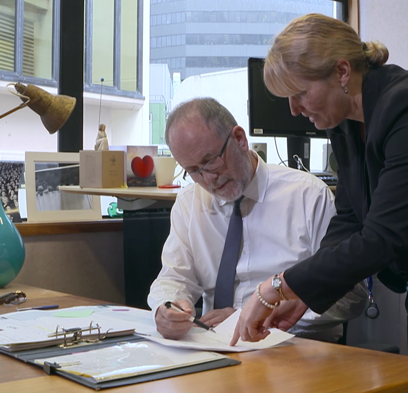 Image of a Judge (Judge Hinton) looking at papers with a member of staff.