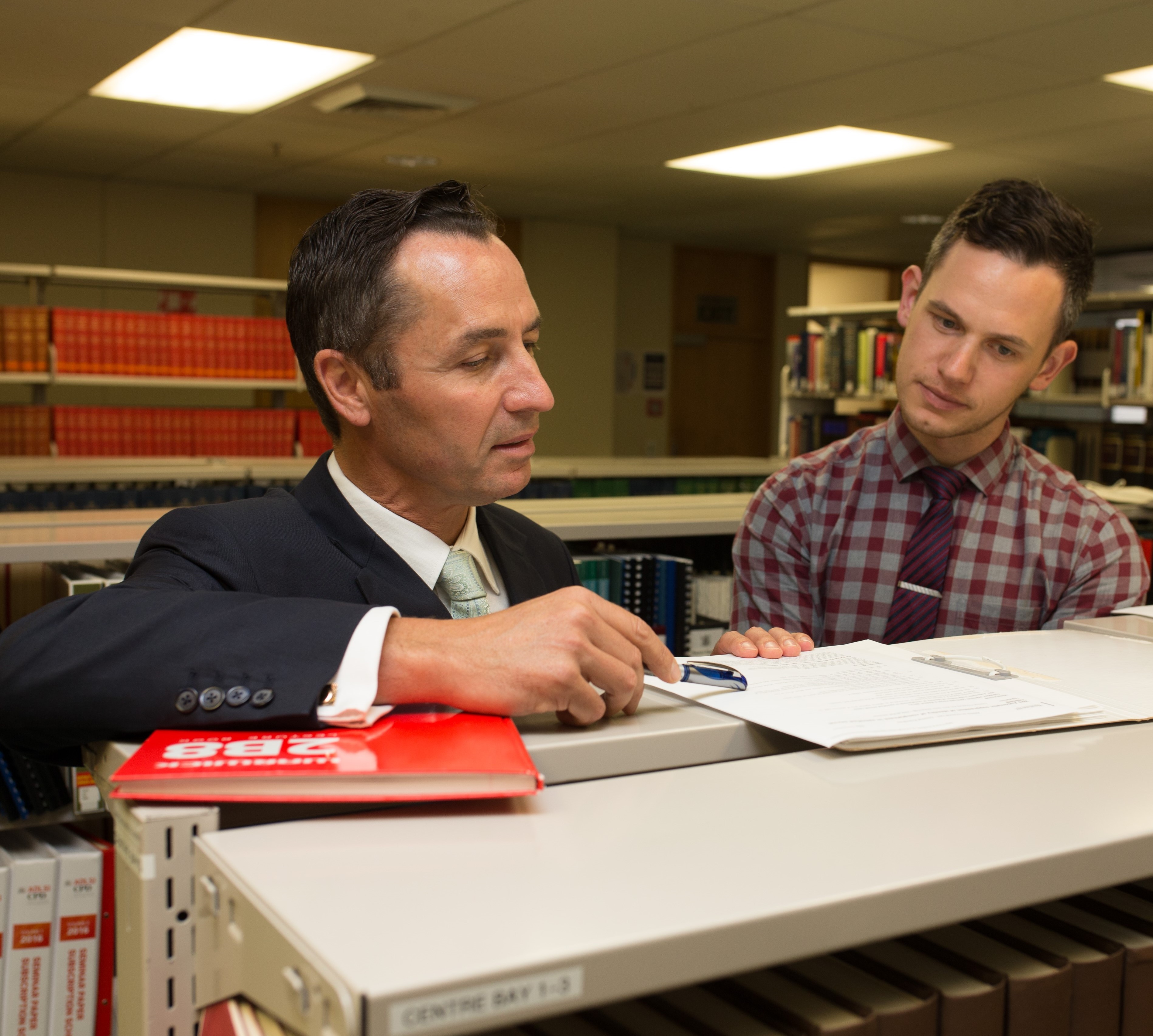 Image of a Judge (Judge Thomas) and a Judges' Clerk in a library, looking at papers.